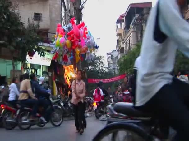 Uma mulher caminha com balões através de uma rua movimentada — Vídeo de Stock