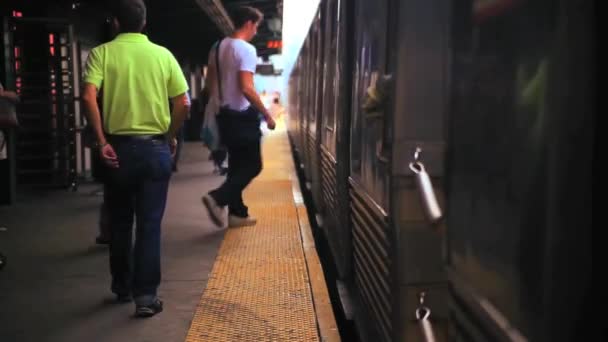 Fahrgäste steigen an einem Bahnhof in einen Zug ein — Stockvideo
