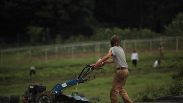 Un hombre empuja un pedazo de equipo de granja — Vídeos de Stock