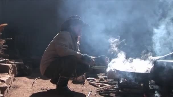 Un vaquero chino se sienta junto a un fuego y fuma — Vídeos de Stock
