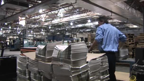 Ein Arbeiter stapelt Zeitungen — Stockvideo