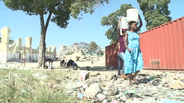 Wanita membawa air melalui reruntuhan setelah gempa bumi — Stok Video