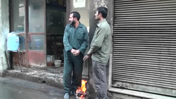 Two men warm their hands over a small fire — Stock Video