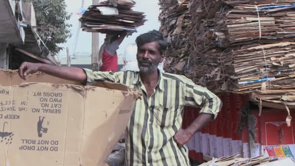 Un homme se penche contre une boîte en carton ouverte — Video