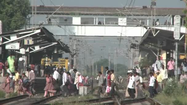 Persone che attraversano i binari di una stazione ferroviaria — Video Stock