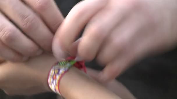 Vriendschap armband wordt geknoopt aan een pols. — Stockvideo