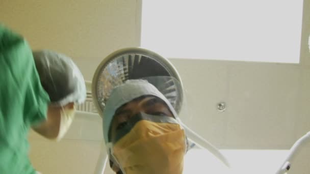 Los cirujanos miran hacia abajo a un paciente — Vídeos de Stock