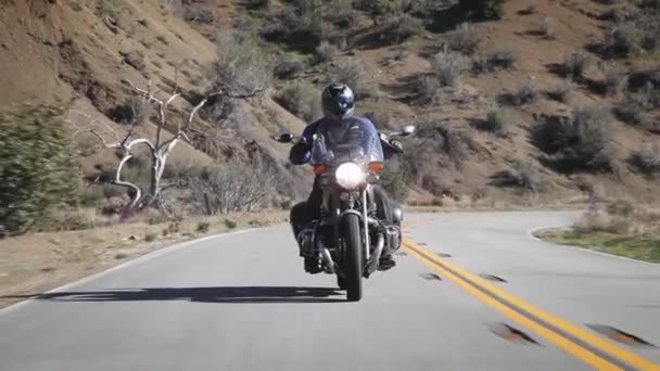 Ένας άνθρωπος βόλτες μια μοτοσικλέτα κάτω ενός ορεινού δρόμου. — Αρχείο Βίντεο