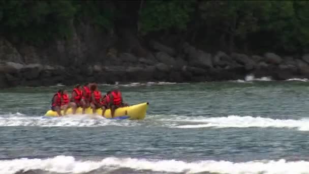 Mensen die dragen rode reddingsvesten rijden door het water op een boot — Stockvideo
