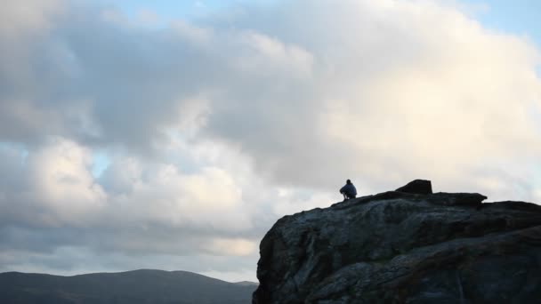 Persona se sienta en la cima de la montaña — Vídeo de stock