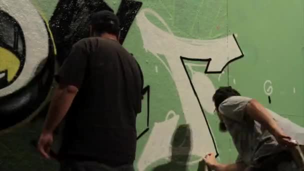 Graffiti being sprayed on a wall by taggers — Stock Video