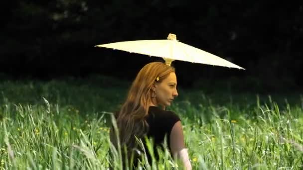 En kvinna med ett paraply i gräs — Stockvideo