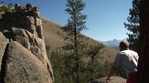 Egy férfi lép rá egy szikla, és úgy néz ki, a távolba. — Stock videók