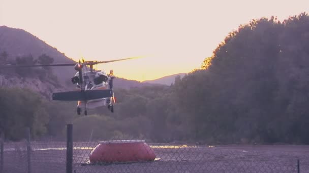 Brandbestrijding helikopter trekt water in een berg wissen in snelle beweging. — Stockvideo