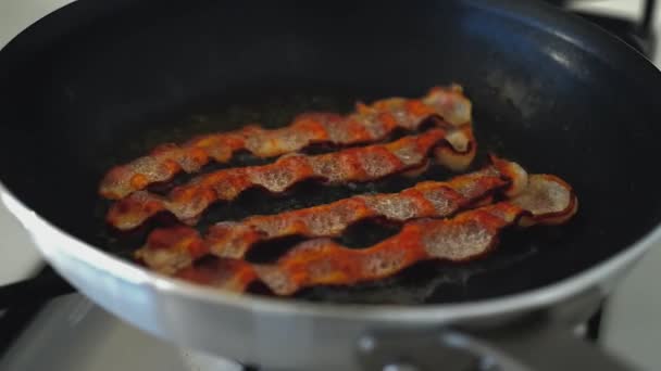 Φέτες μπέικον ψημένο στη σχάρα σε ένα skillet. — Αρχείο Βίντεο