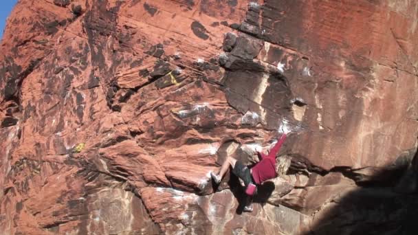 Een vrouw klimt de zijkant van een berg. — Stockvideo