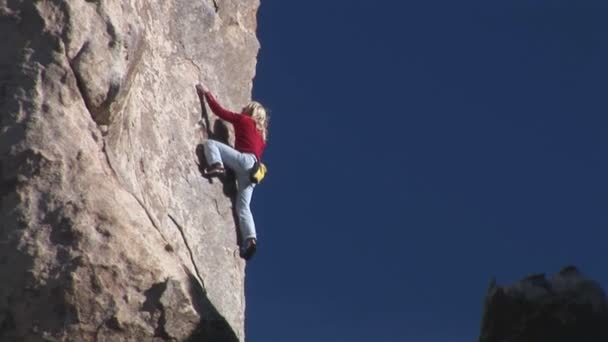 Una mujer sube por el lado de una montaña . — Vídeo de stock