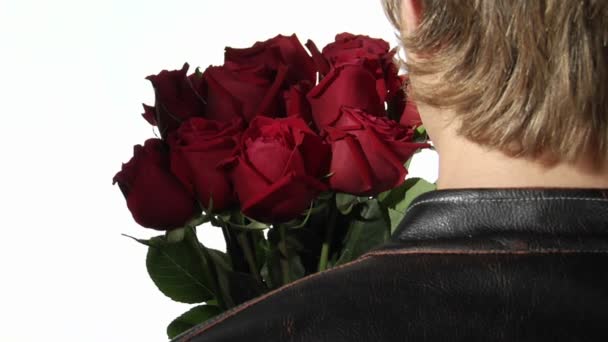 A woman leans in to whisper in the ear of a man holding roses. — Stock Video