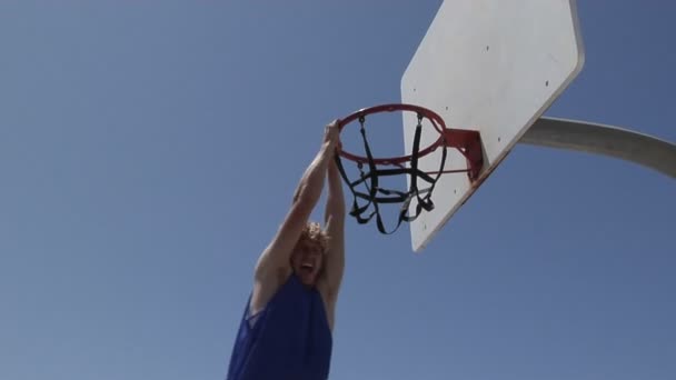 Un jugador de baloncesto golpea dunks mientras está de pie en una escalera . — Vídeos de Stock