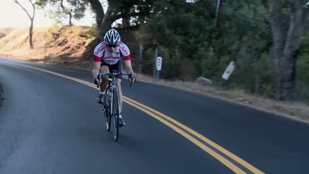 Un ciclista en un camino arbolado rural . — Vídeos de Stock