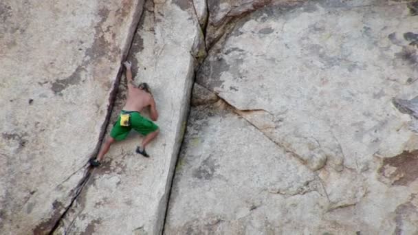 En ung man klättrar upp på en bergssluttning. — Stockvideo