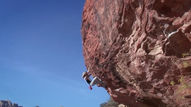 Egy nő mászik egy szikla. — Stock videók