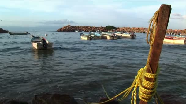 Un bateau à moteur attaché à un poteau de quai roche dans les vagues . — Video