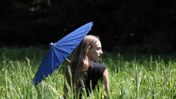 En kvinna sitter på en gräsbevuxen område — Stockvideo
