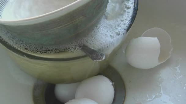 Вода течет в раковину, содержащую блюда и яичные скорлупы — стоковое видео
