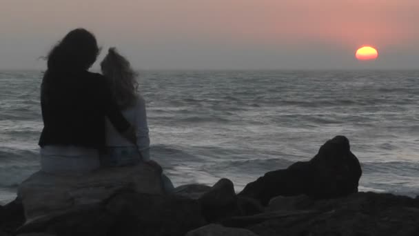 一位母亲和她的女儿坐在一块岩石，面朝大海 — 图库视频影像