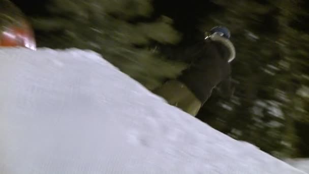 Um cavaleiro de snowboard bate um salto à noite . — Vídeo de Stock