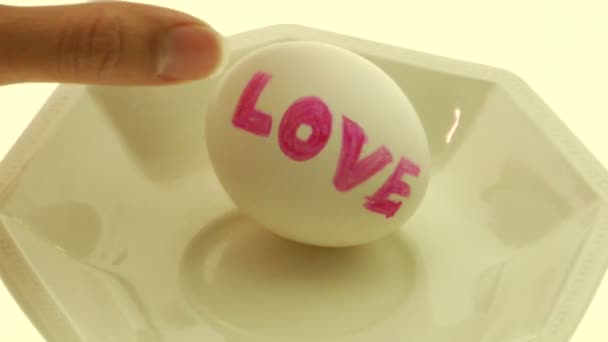 Kobiecej ręki odbiera i gniecie jajka do miski ze słowem "miłość" — Wideo stockowe
