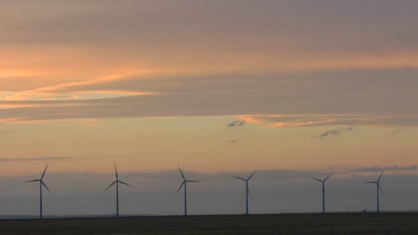 Una línea de molinos de viento se silueta — Vídeo de stock