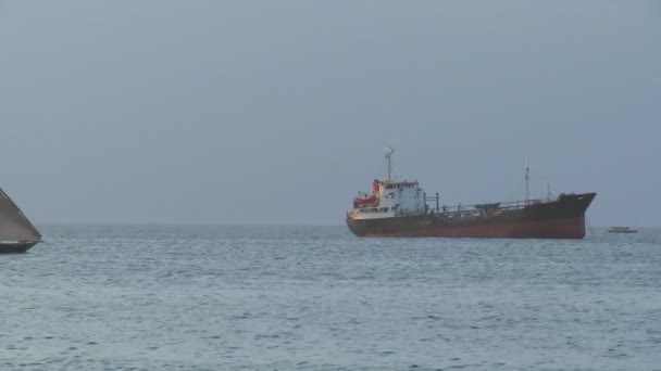 Ein Dhau-Segelboot segelt an einem Frachtschiff vorbei — Stockvideo