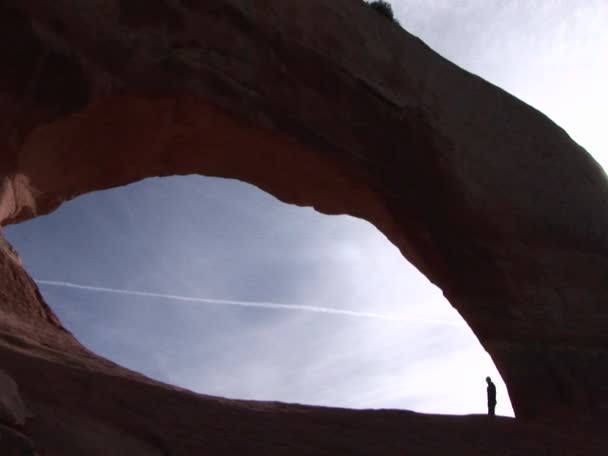 Человек ходит под аркой из песчаника — стоковое видео