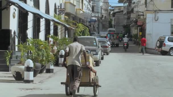 A man pushes a hand cart along boulevard — Stock Video