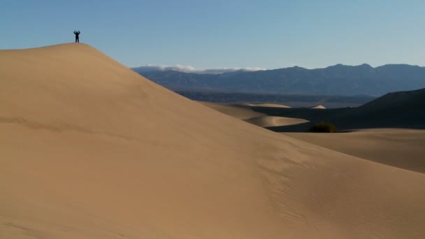 Une personne saute sur une dune déserte — Video