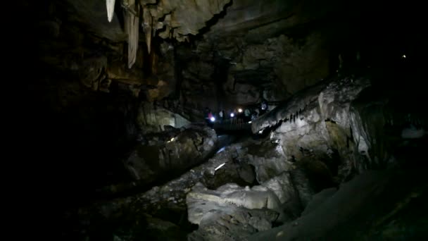 La gente explora una cueva oscura con linternas — Vídeos de Stock