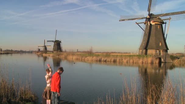 Kinderen spelen naast de windmolens — Stockvideo