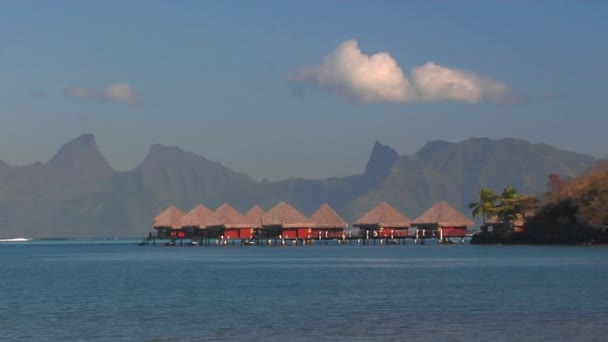 Tahitské chaty na vodě s řádkem hřeben hory v dálce. — Stock video