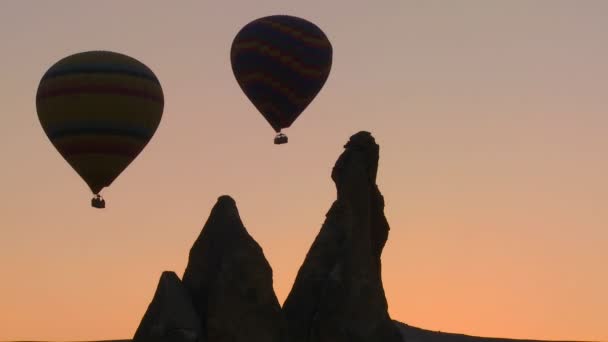 Globos de aire caliente siluetas contra un pico de montaña — Vídeo de stock