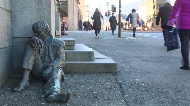 Pessoa senta-se perto de uma estátua que descreve uma pessoa sem-teto — Vídeo de Stock
