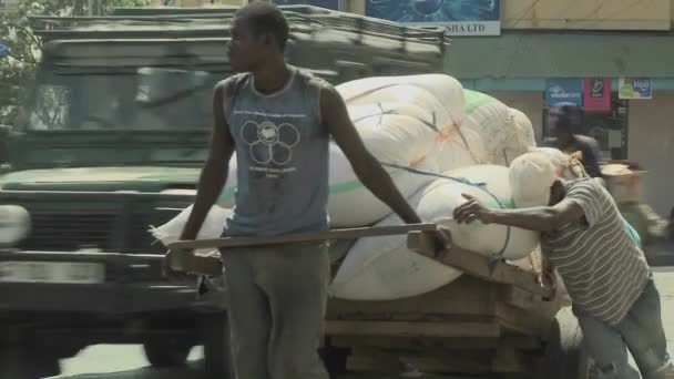 Los hombres empujan un carro por una calle — Vídeos de Stock