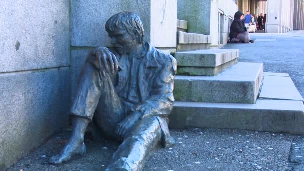 Person sits near a statue depicting a homeless person — Stock Video