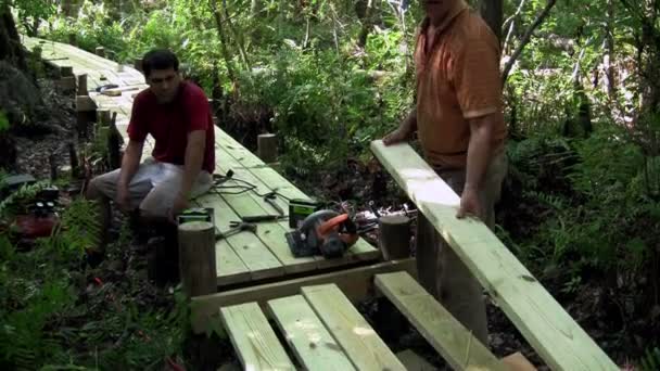 A father and son work on a wooden walkway — Stock Video