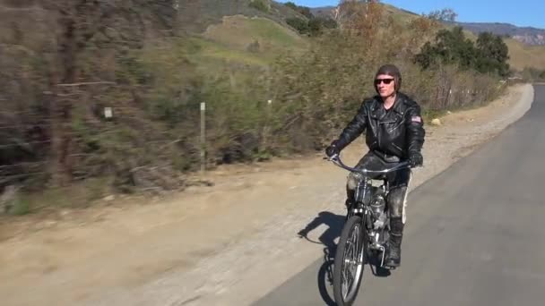Um homem conduz uma bicicleta motorizada — Vídeo de Stock