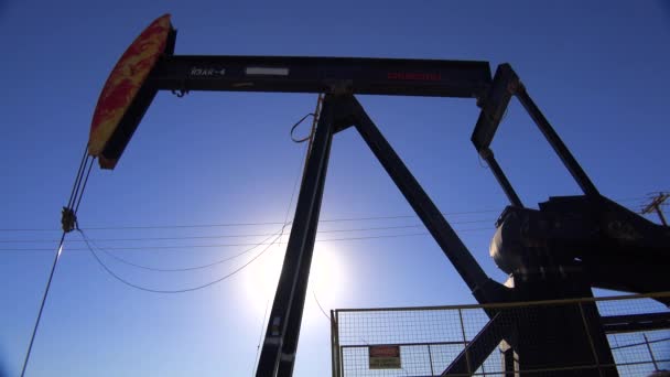 Pompe à huile derrick contre le ciel bleu . — Video