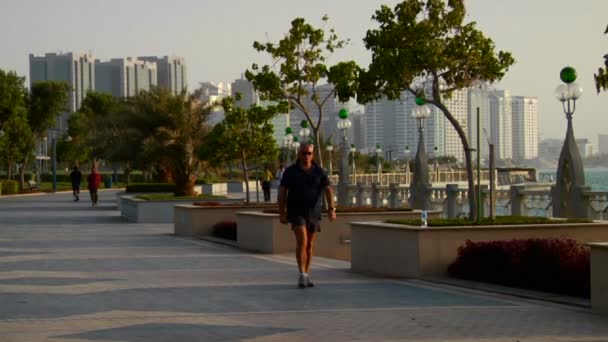 Los corredores corren al lado del hermoso horizonte de Abu Dhabi en los Emiratos Árabes Unidos . — Vídeos de Stock