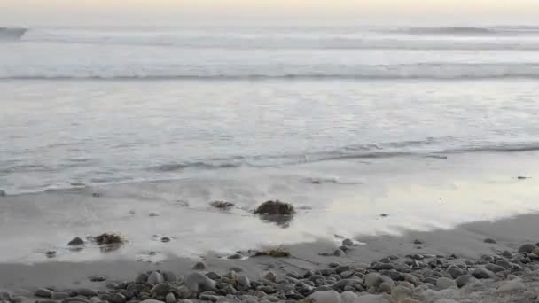 Wellen, die bei Sonnenuntergang an Land spülen — Stockvideo