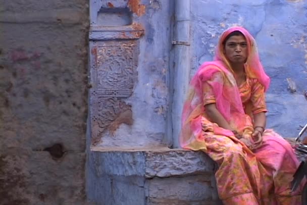 Γυναίκα κάθεται σε πολύχρωμα ρούχα — Αρχείο Βίντεο
